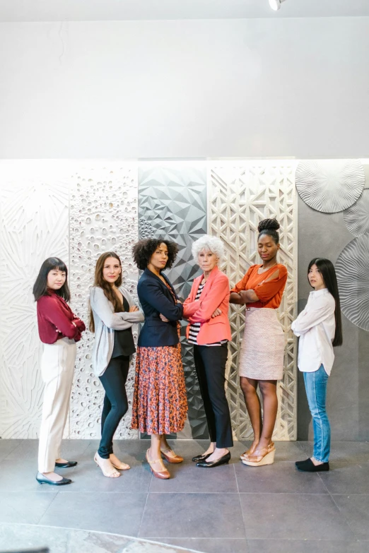 four women are standing next to one another in front of artwork