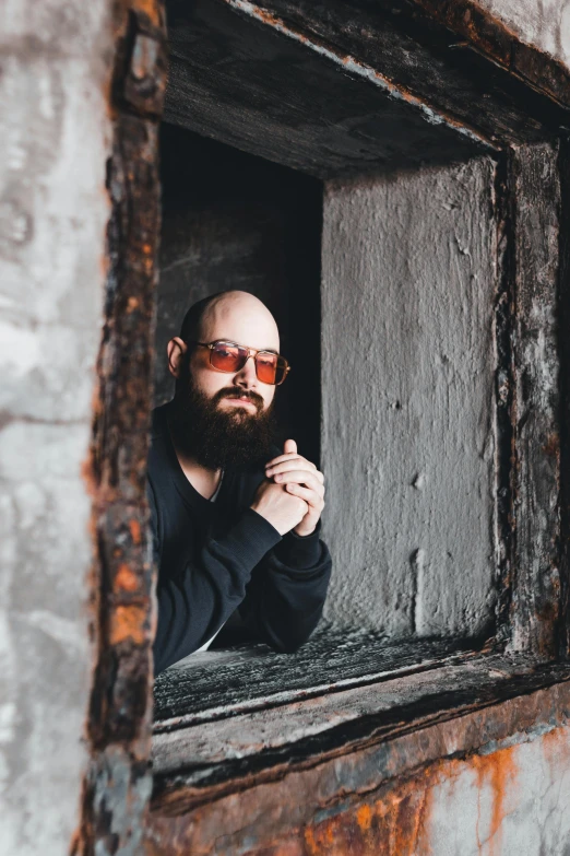 a man looking out of a window on top of a brick wall