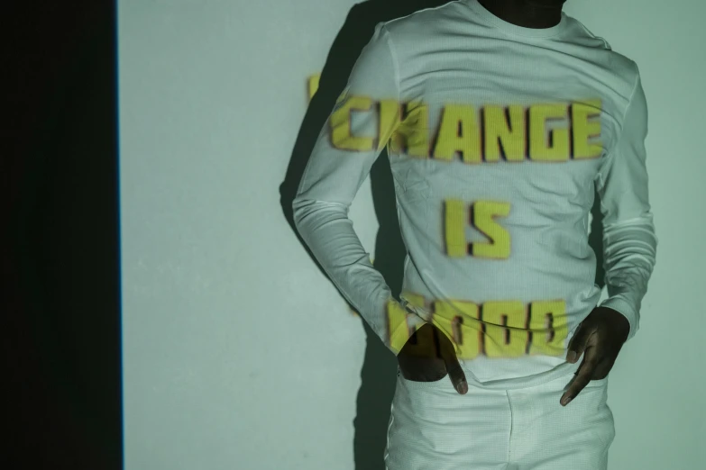 a man in a white top standing against a wall