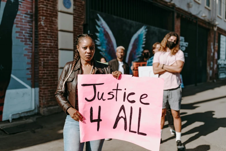 a black girl holding a pink sign that says justice 4 all