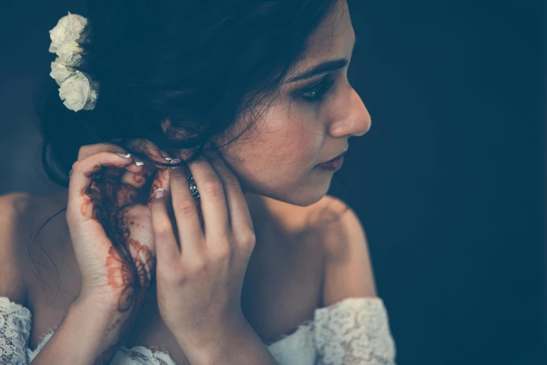 a woman wearing a wedding dress holding her hands to her face and her  dripping off her arm