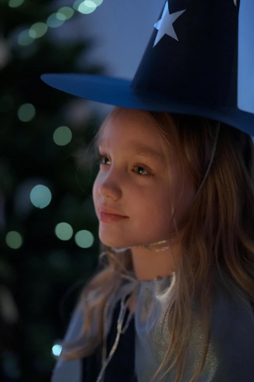 little girl in a patriotic hat looking ahead with holiday tree in the background