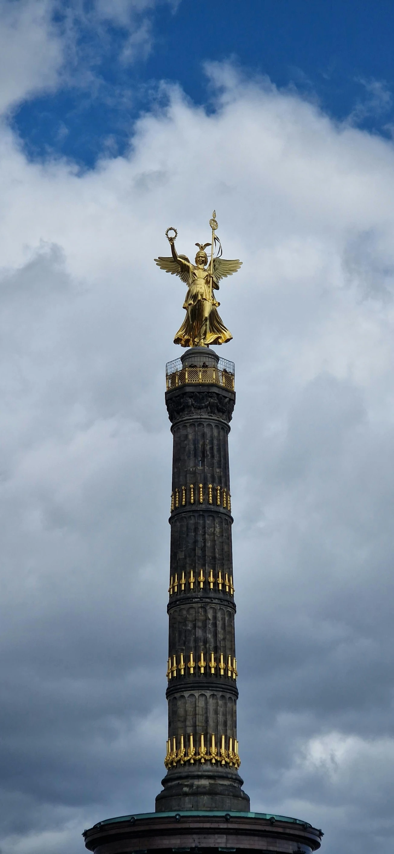 an ornate golden statue stands atop a monument