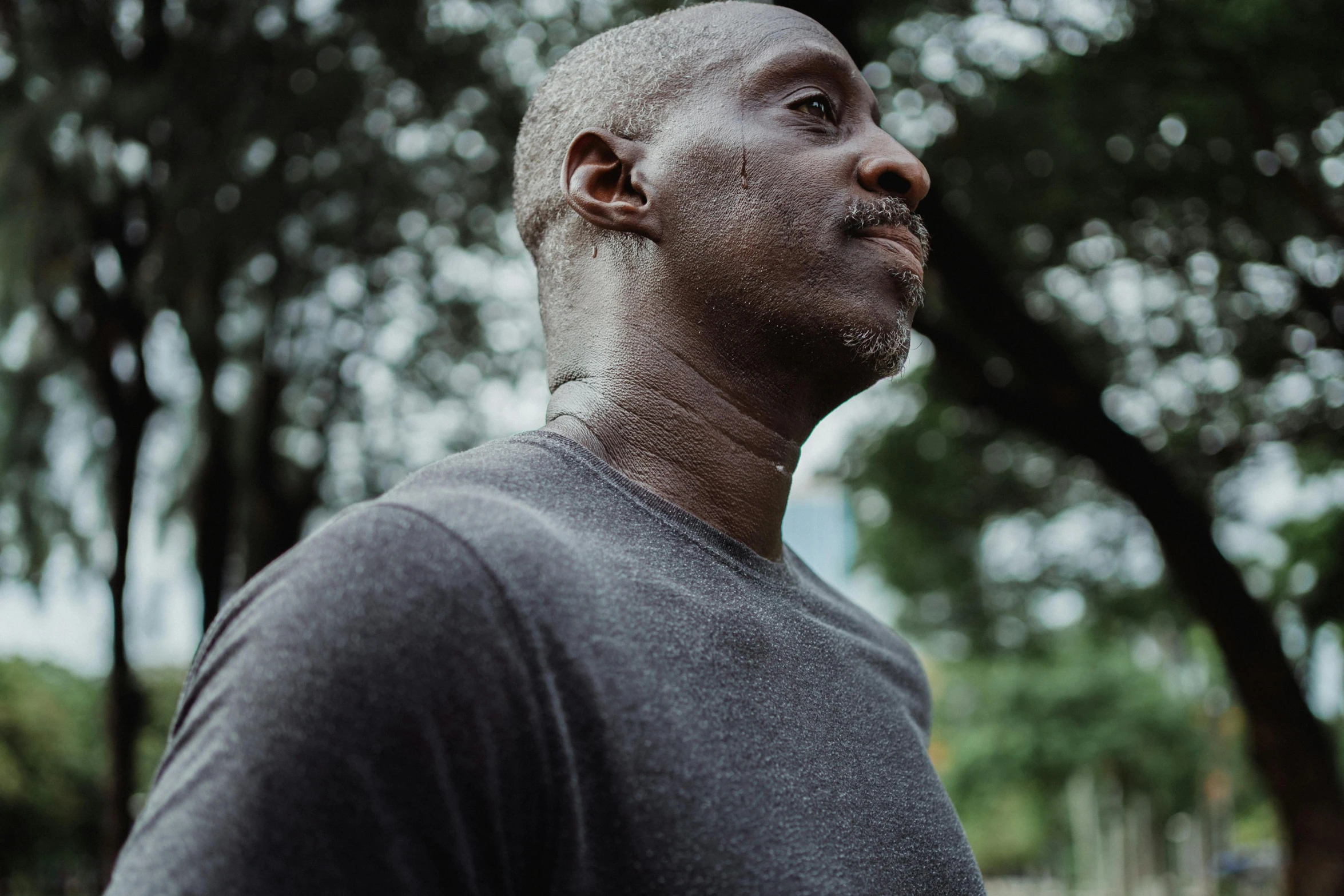 a black man in a gray shirt looking off in the distance