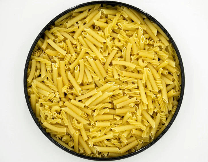 a bowl filled with yellow pasta next to a cup