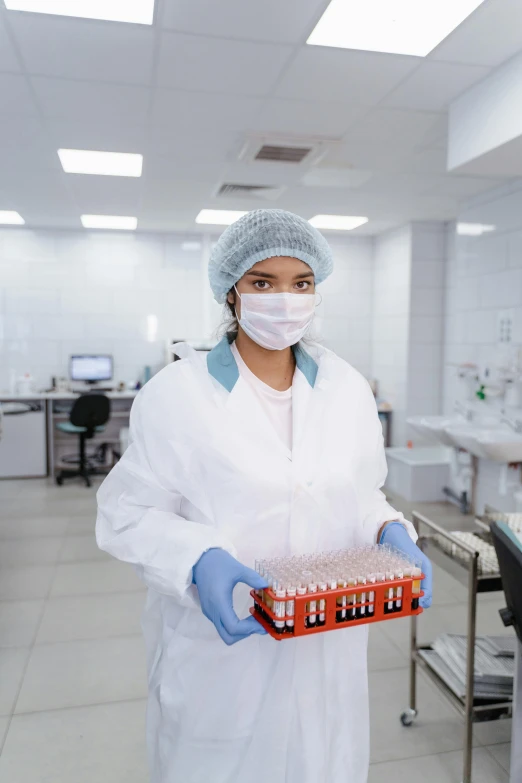 a woman in a laboratory holds a box containing samples