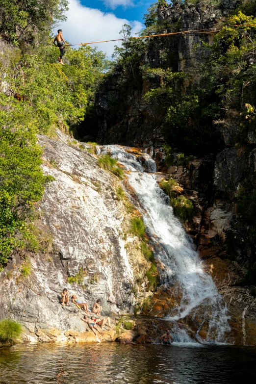 man jumping off the side of a waterfall into the water