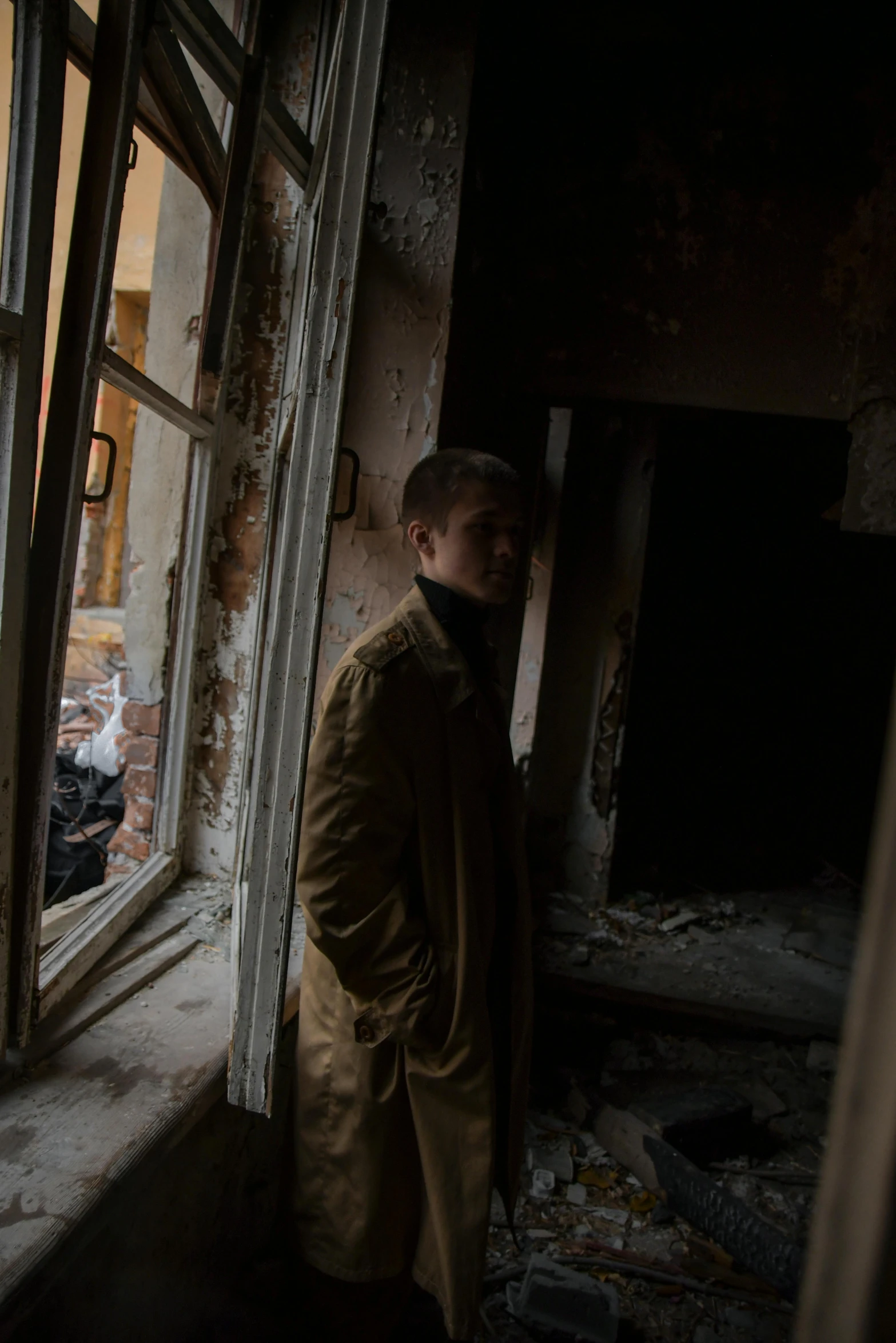 a man in brown coat standing in room with open windows