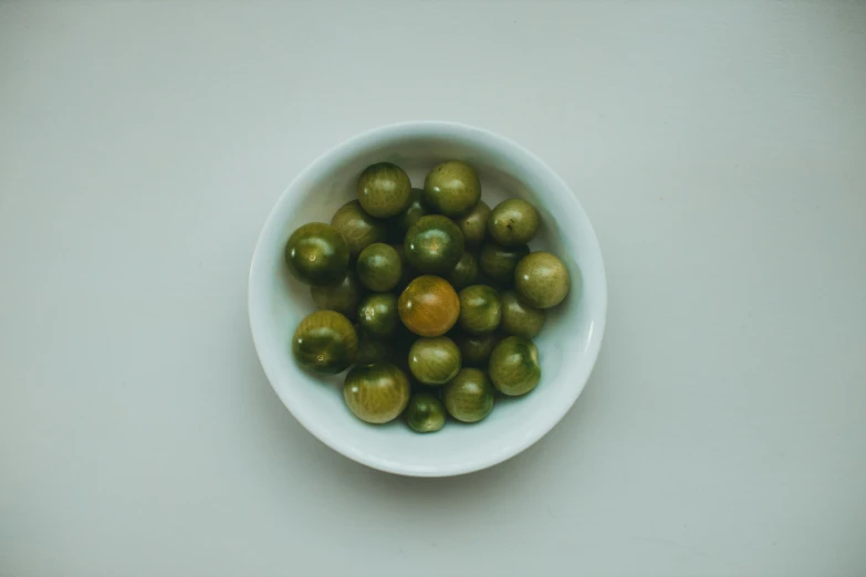 a bowl filled with green olives on top of a table