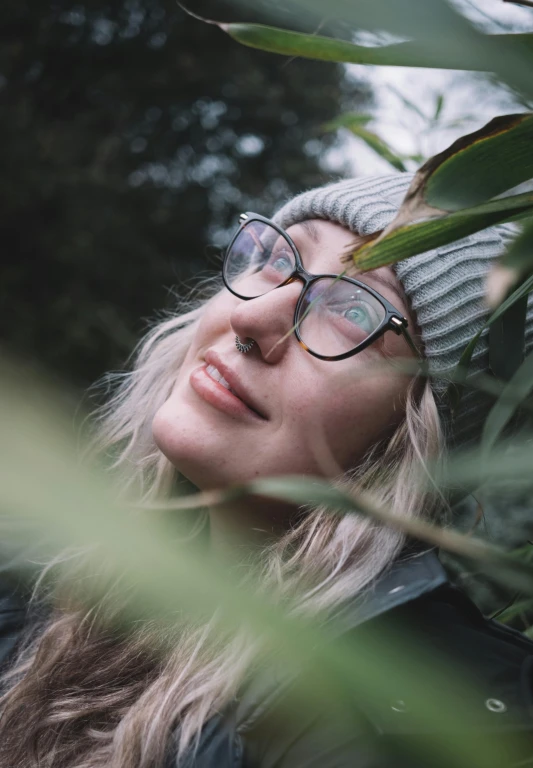 the woman is standing between palm leaves