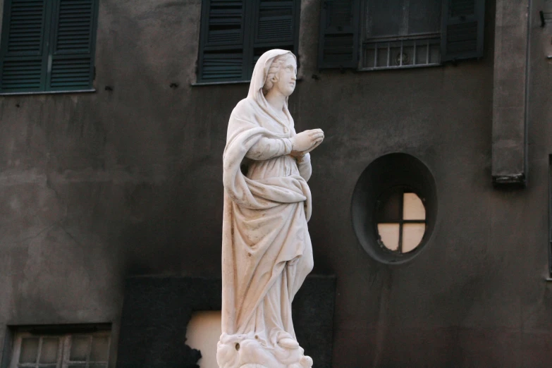 a stone statue standing next to a tall building