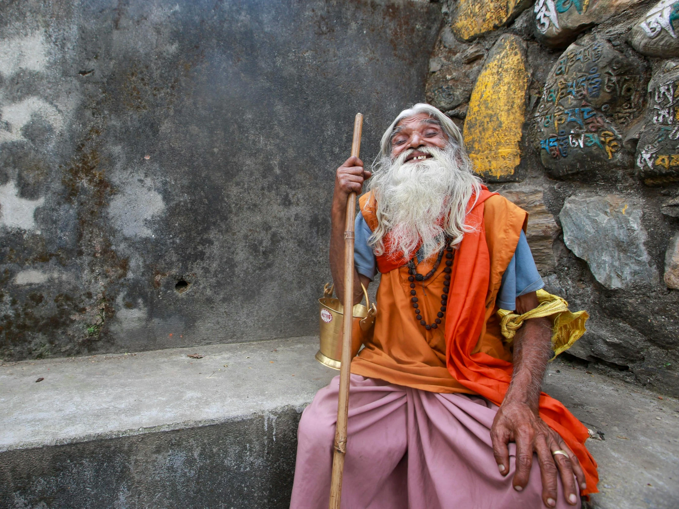 an old man with white hair and beard sitting on cement step