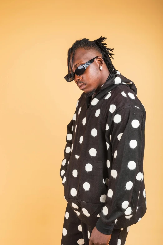 young man in a polka dot jacket is carrying a suitcase