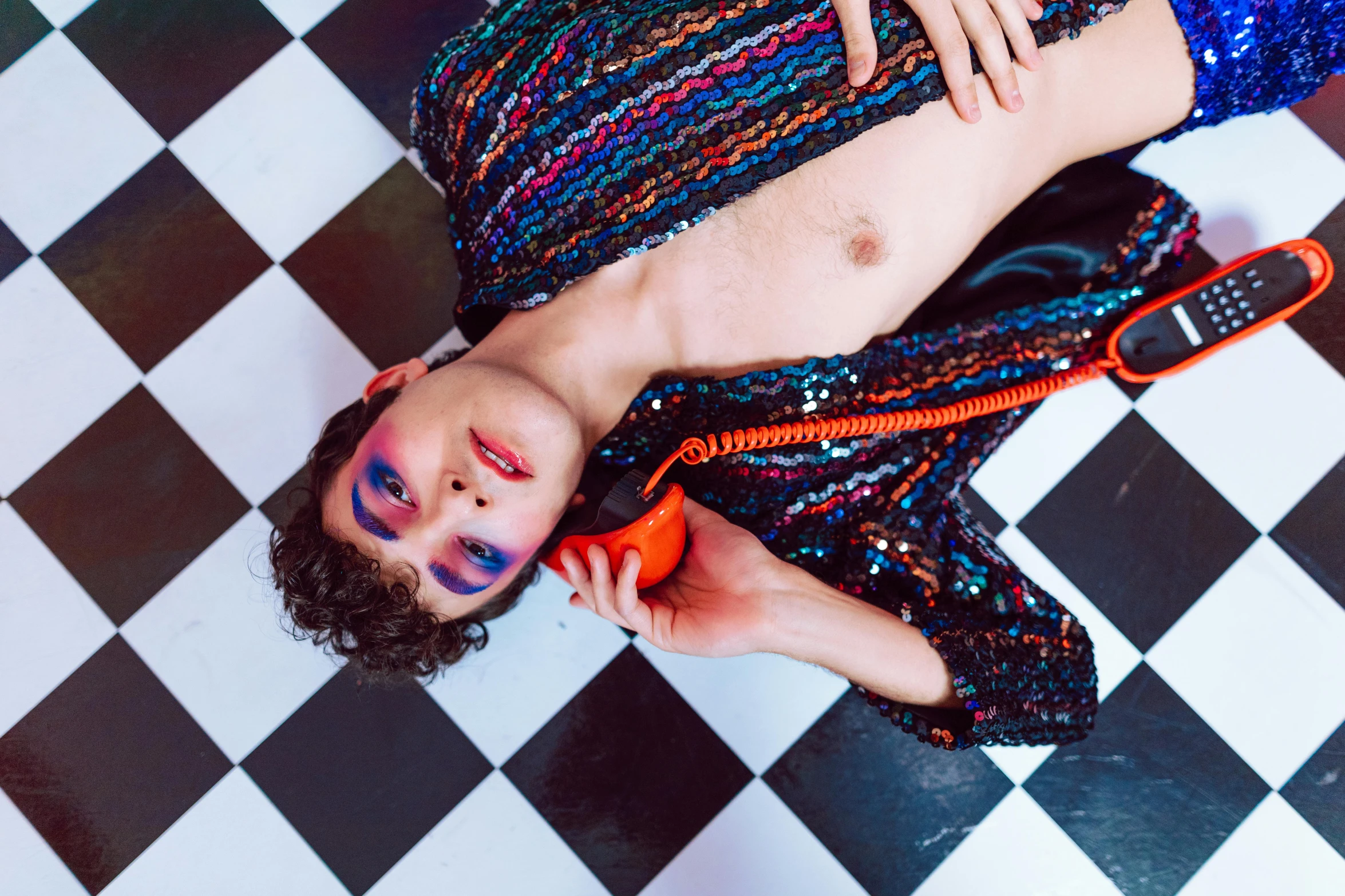 a young man is laying on a checkered floor while talking on the phone