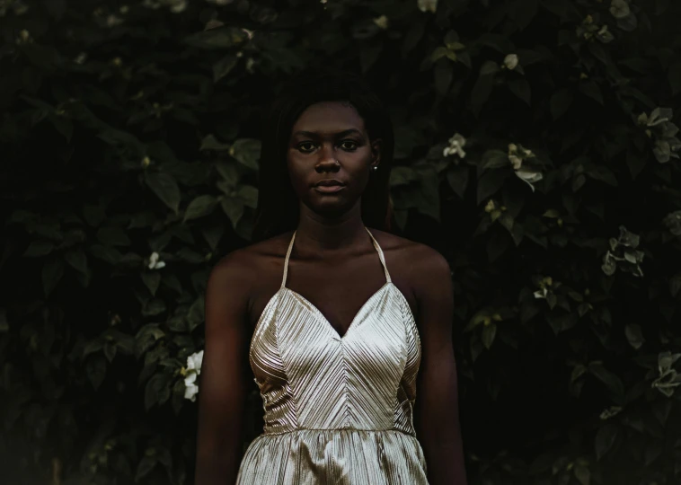 a young woman poses in a dress by some trees