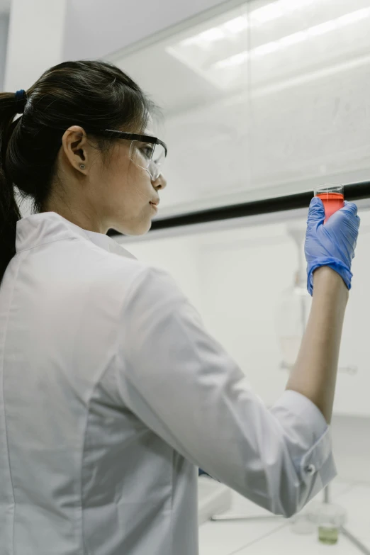 woman in lab coat and gloves looking at screen