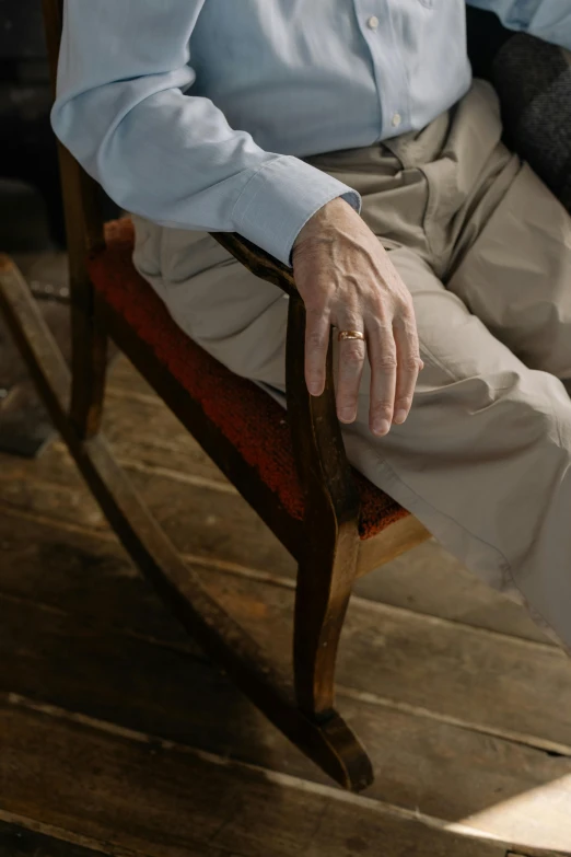 a man sitting in a chair while wearing a ring on his finger