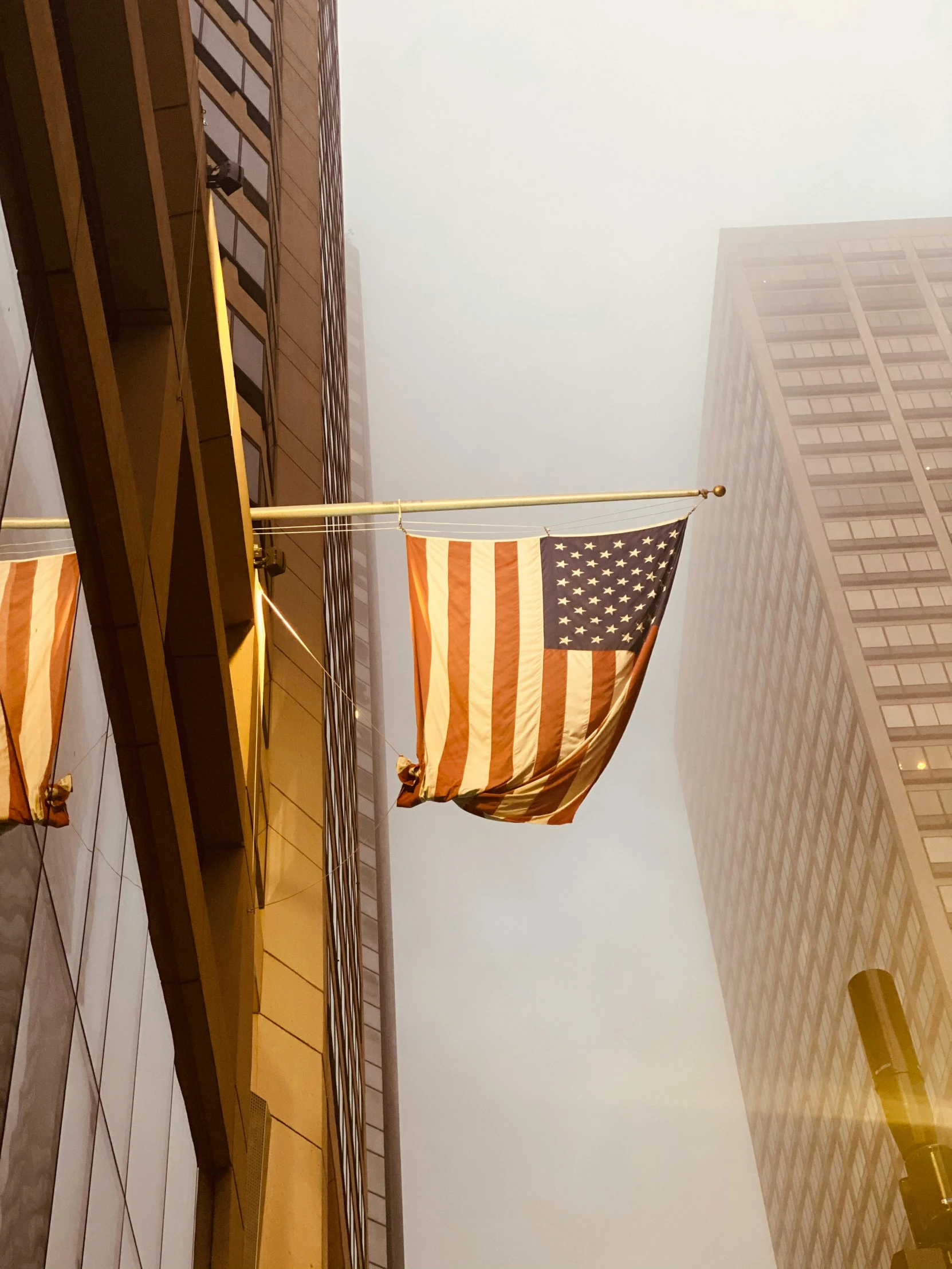 two american flags are strung up by ropes from a building