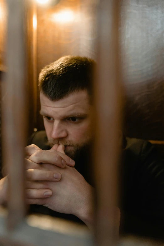 man sitting in chair at home looking through bars