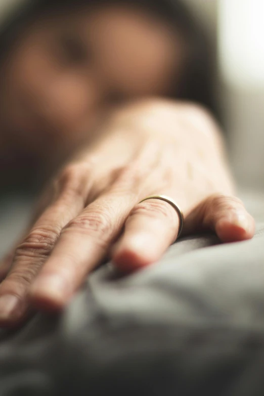 a person laying on the bed with a wedding band