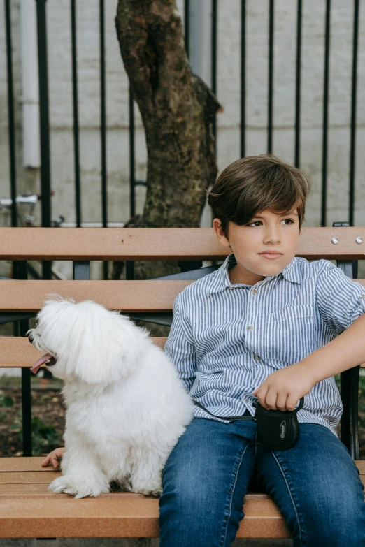  sitting on a wooden bench next to his white dog