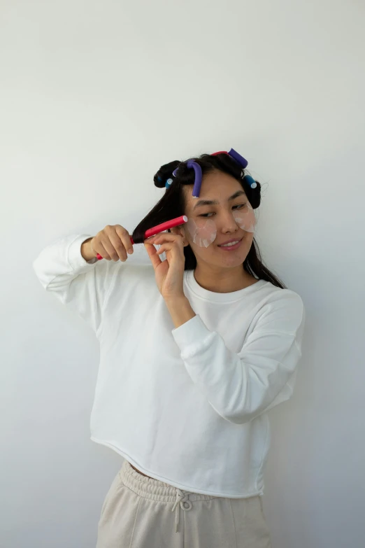 a woman holding a hairbrush in her right hand and combing her other hair