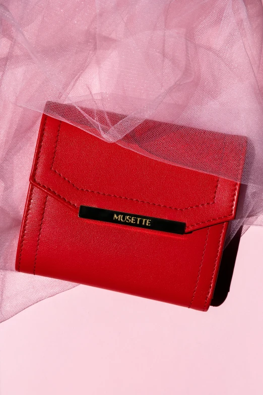 the red purse is placed against the white fabric