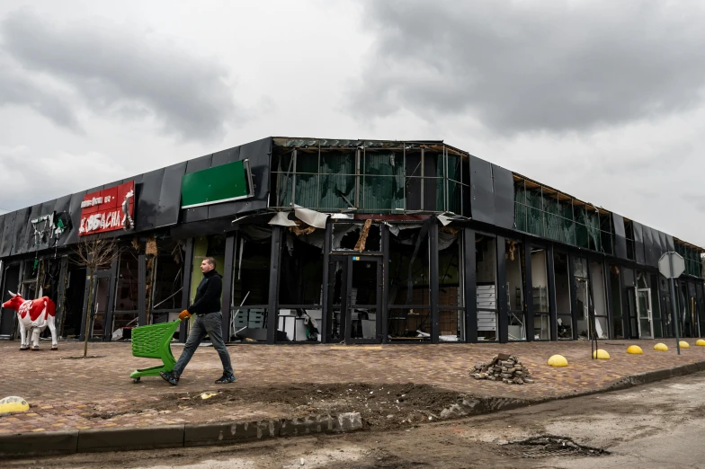 people with green bags walk in front of a large building that is under construction