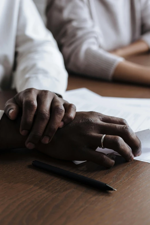 hands resting on a wood surface with papers spread in front