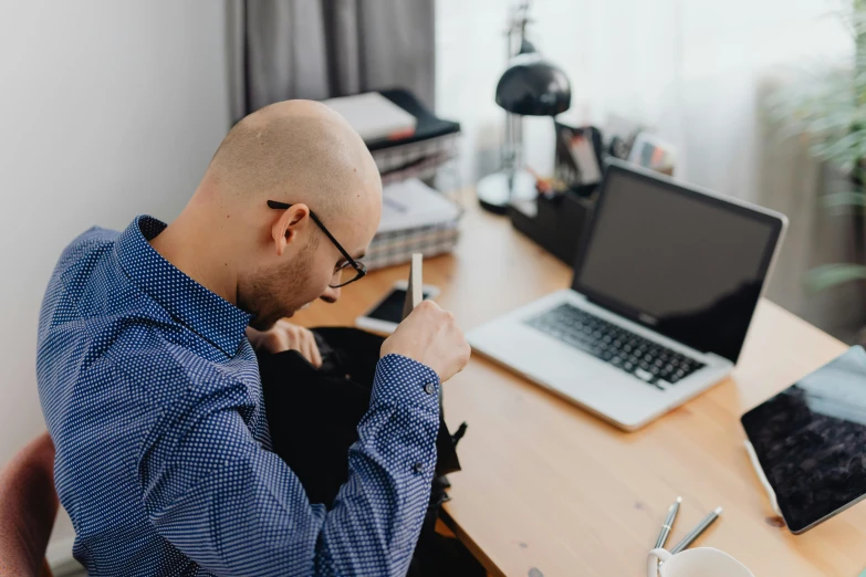 a bald man sitting at a table writing in his notebook