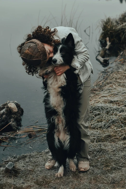 a dog is hugging a woman in front of water