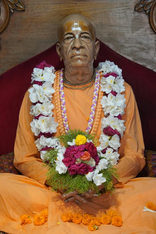 statue of buddha with flower garland at indoor gathering area