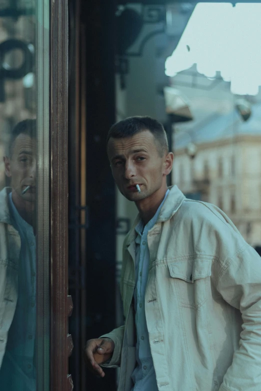 a man standing near a door with his cigarette in his mouth