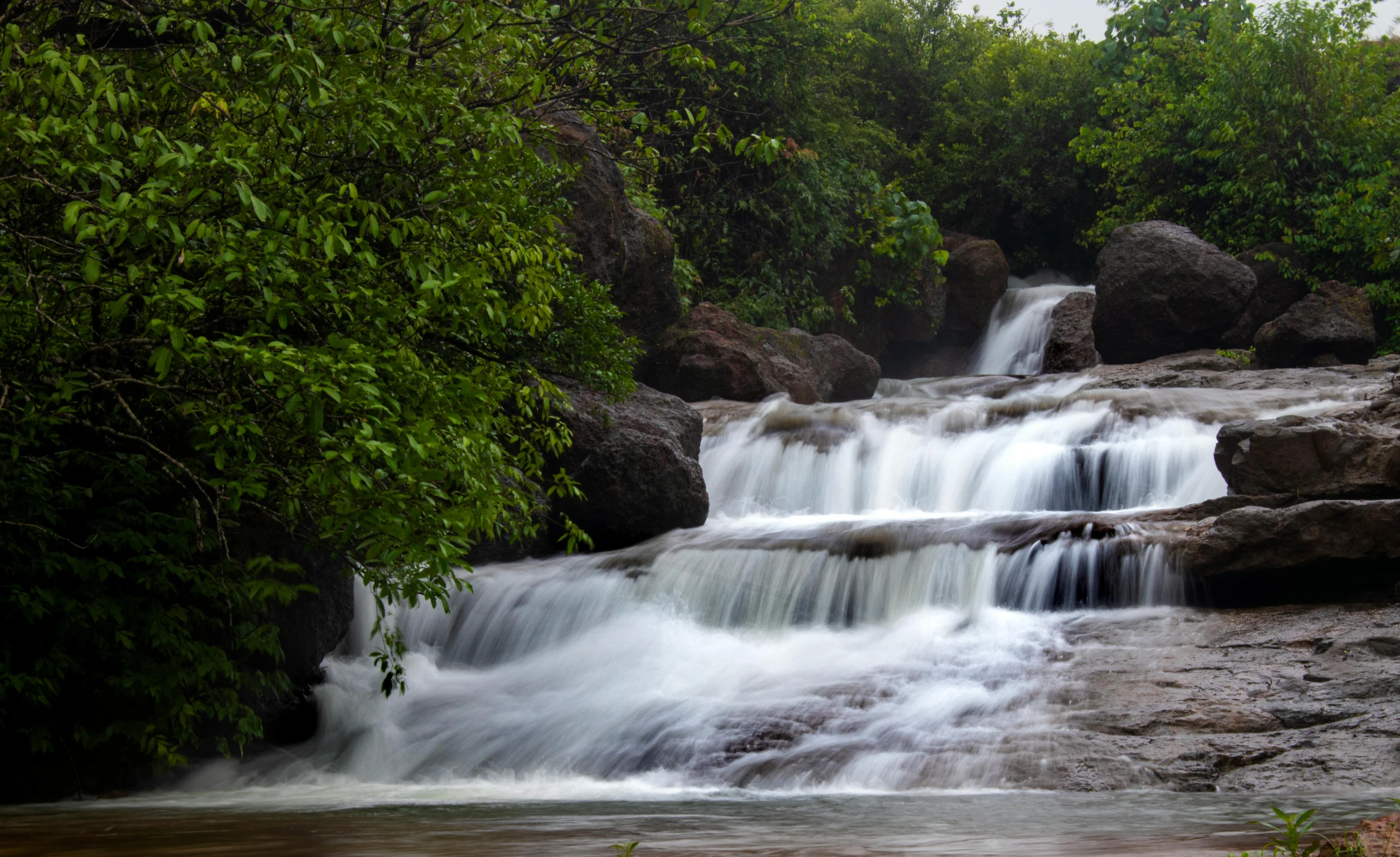 a large waterfall near some rocks and trees