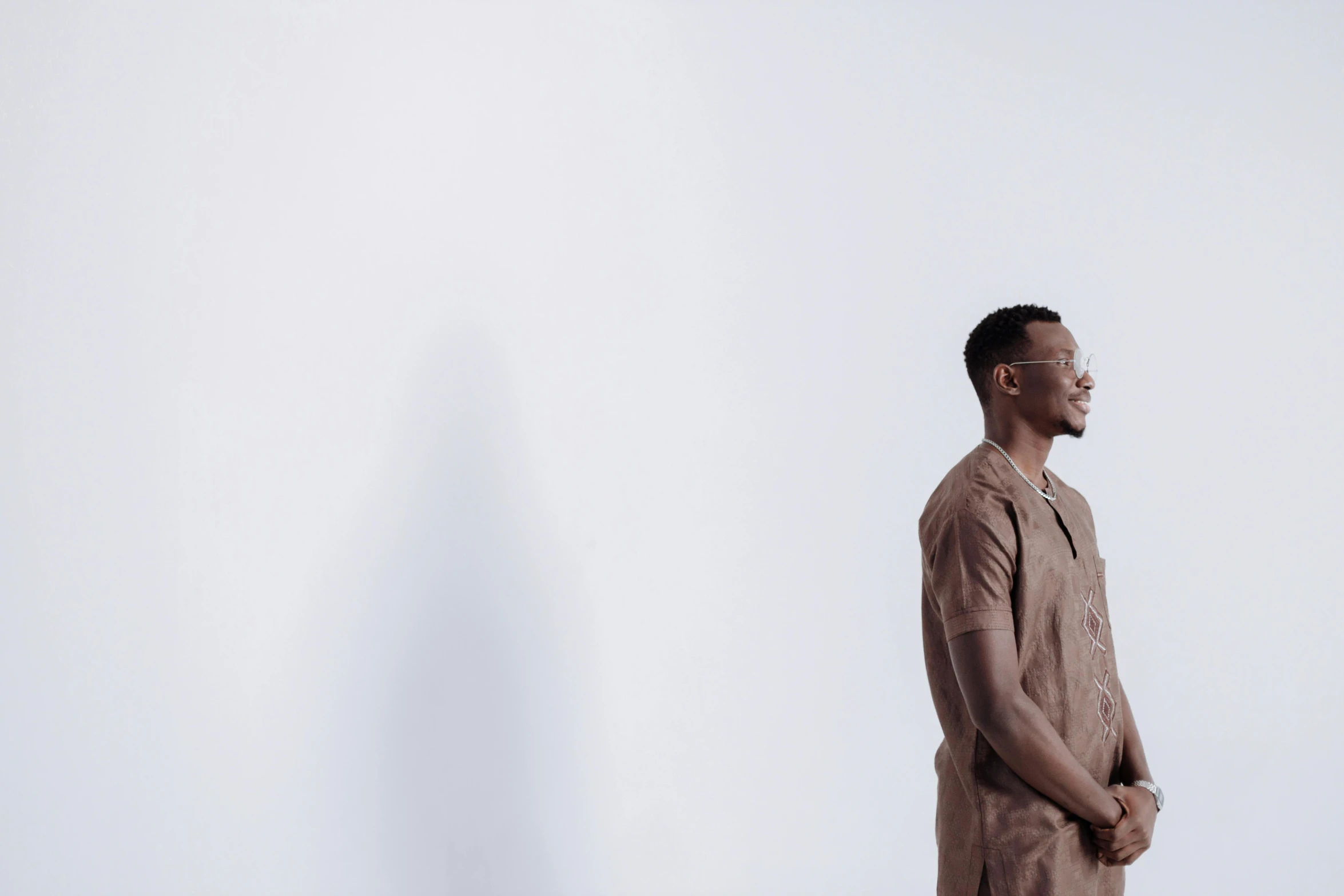 man in an orange outfit standing near a white wall