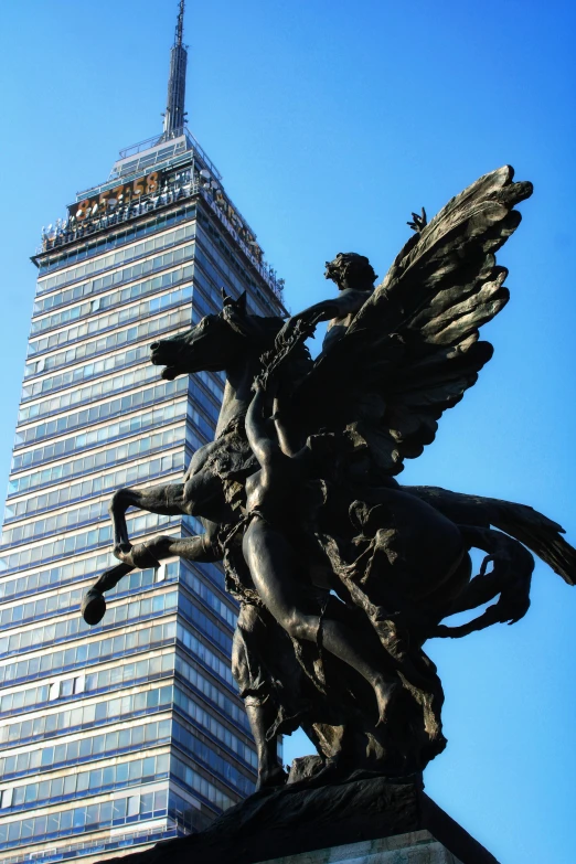 the statue is beside a skyscr that has two angels