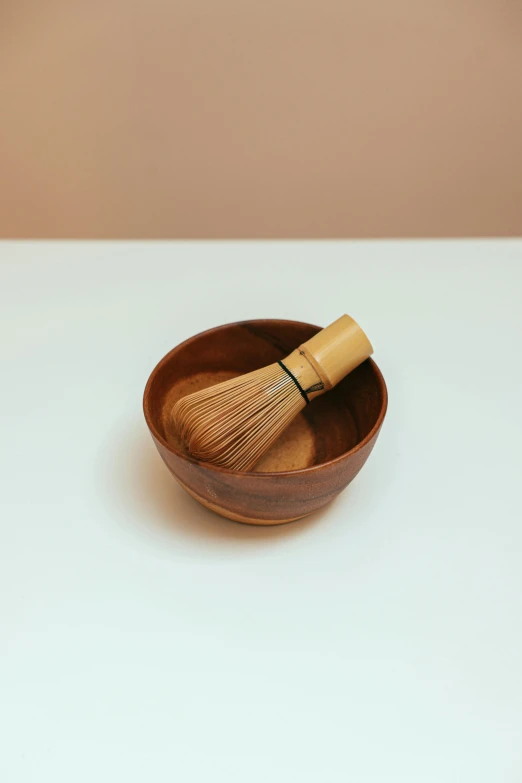 small brown wooden bowl with bamboo brush in it