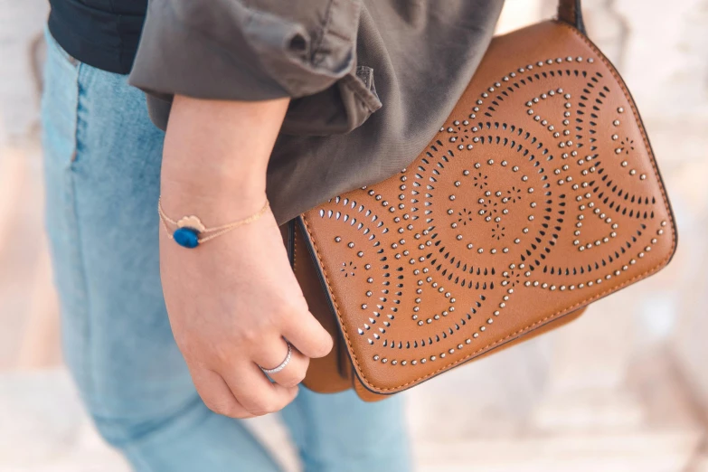 woman's hand holding a tan leather purse