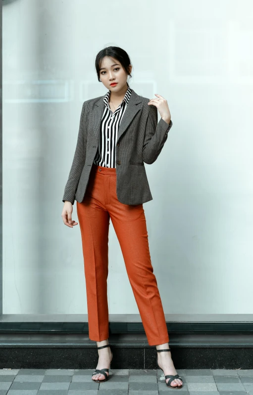 a woman in an orange pants stands by a wall