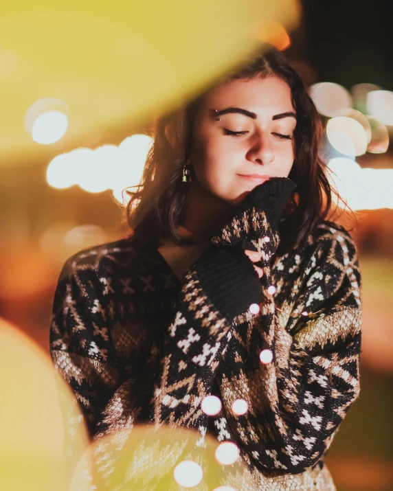 woman in black and gold sweater holding up a phone