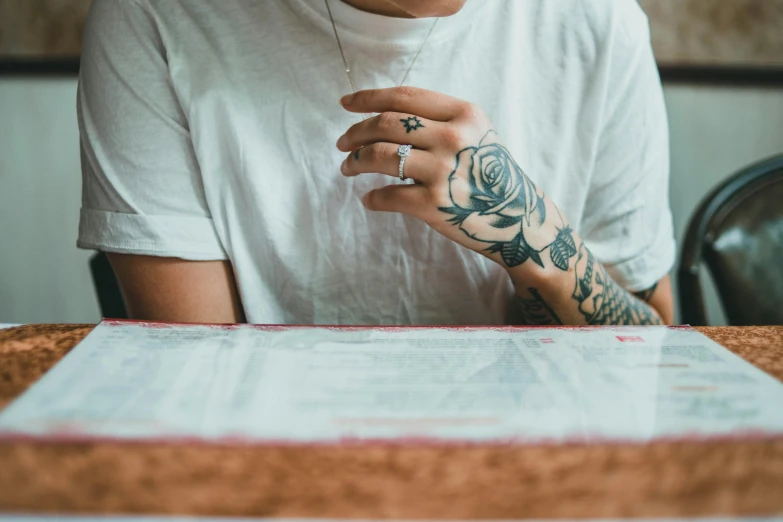 a person sits with a tattooed arm holding a phone