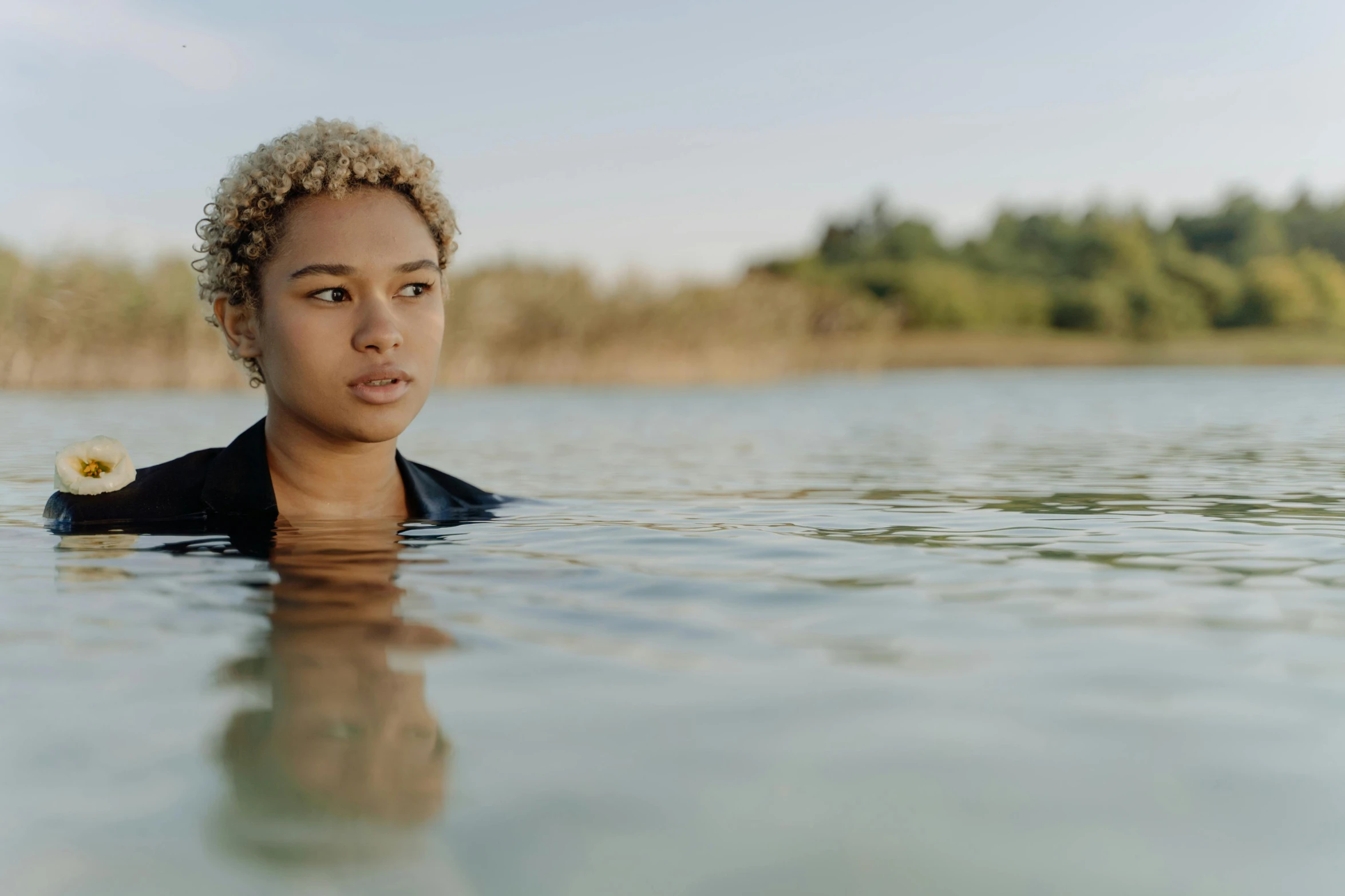 a man is swimming in the water with trees behind him