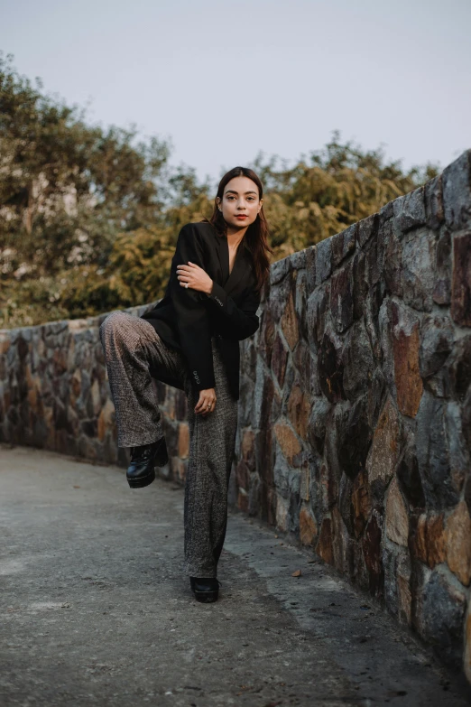 a beautiful young woman standing by a stone wall