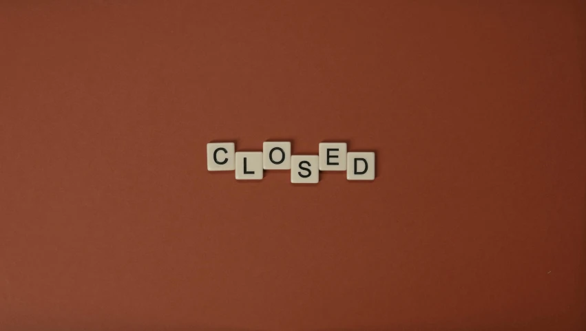 scrabble blocks spelling closed and missing on a red surface