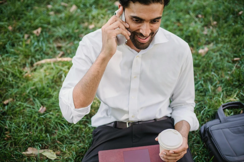 a man wearing a suit talks on the phone while holding a drink