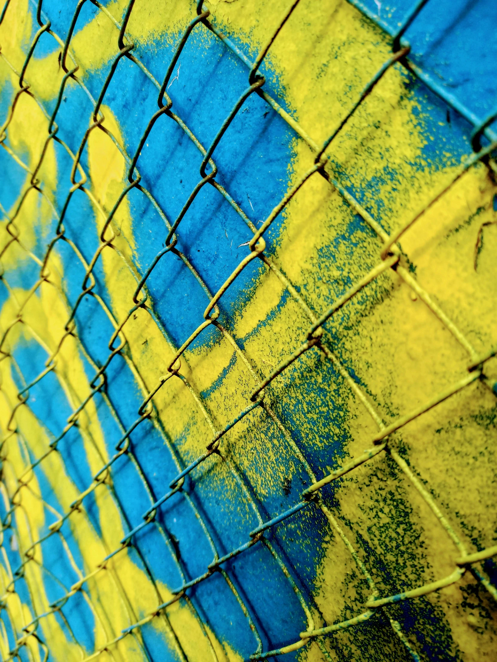 colorful wall with a chain link fence that has been painted yellow