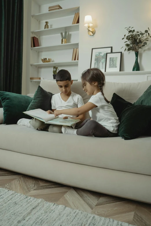 two children are reading books on a couch