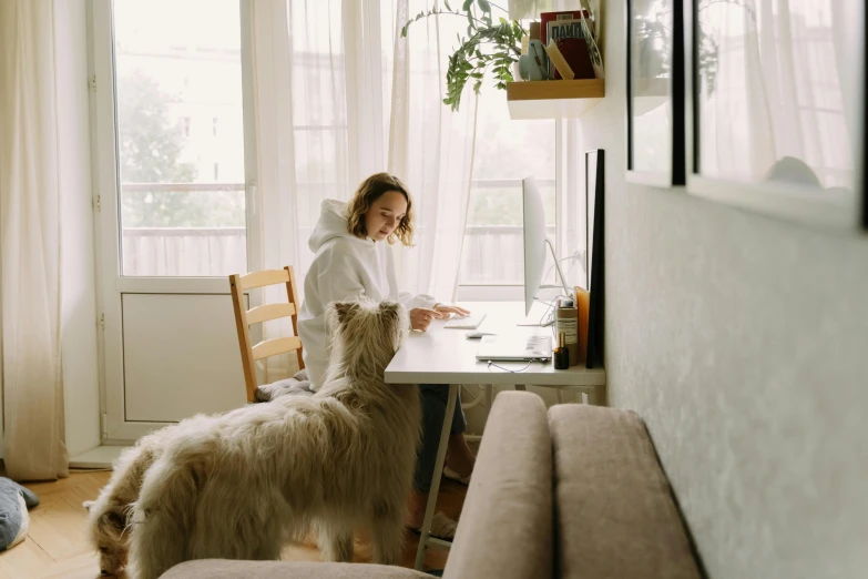 a woman sitting in a chair with her dog standing up next to the desk