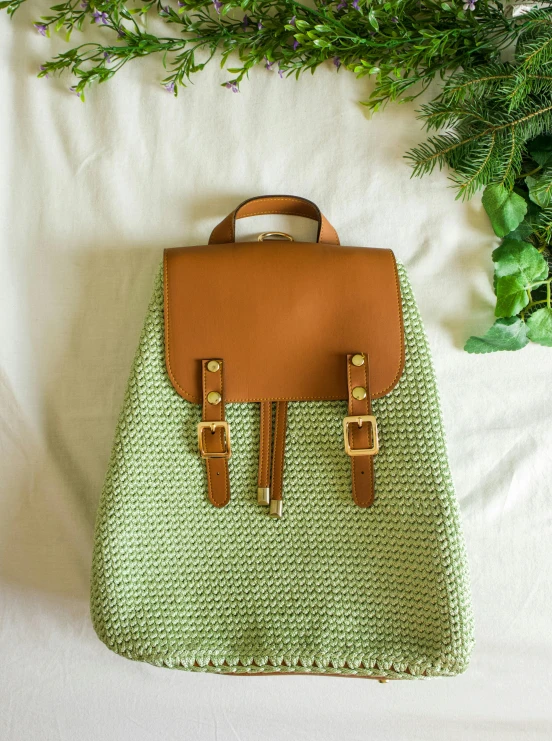 a green bag sitting on a bed next to a plant