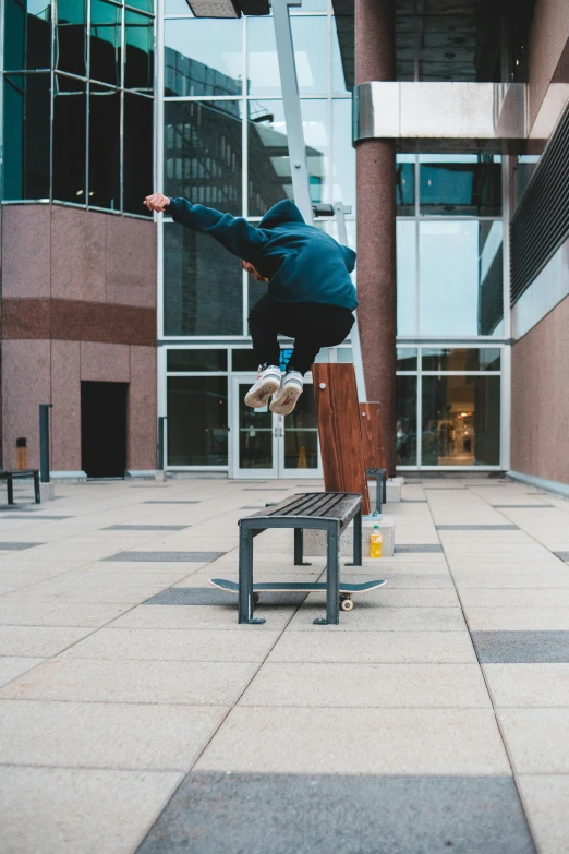 a young person doing a trick on the back of a wooden bench